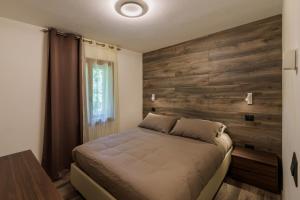 een slaapkamer met een bed en een houten muur bij AREA Apartments Madonna di Campiglio in Madonna di Campiglio