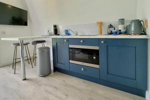 a blue kitchen with a counter and a sink at Bombie Glamping Pod in Grantown on Spey