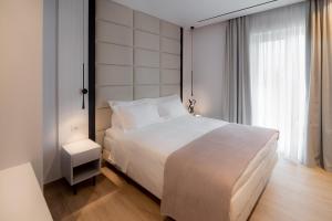 a bedroom with a white bed and a large window at Contessa Bianca San Rocco Luxury Residences in Corfu