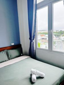 een bed met een handdoek naast een raam bij Pema House Hotel in Da Thanh