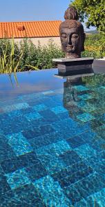 a swimming pool with a statue in the water at Loft & spa d'Autan in Villefranche-de-Lauragais