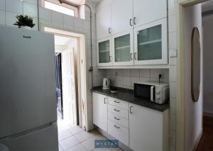 a kitchen with white cabinets and a microwave at MyStay - Lira's Guest House in Porto