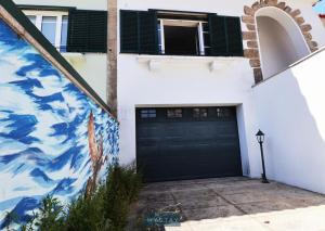 une maison avec une porte noire et une fresque murale dans l'établissement MyStay - Lira's Guest House, à Porto