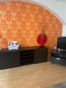 a room with an orange wall with a guitar on it at City Apartment Dresden in Dresden