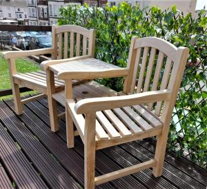 two wooden chairs sitting on top of a deck at Driftwood Studio in Cromer