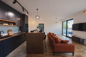 a kitchen with black cabinets and a bar with a couch at KOKO VILLAGE in Podgorica