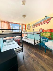 a room with three bunk beds and a sink at The Flying Pig Beach Hostel, ages 18 - 40 in Noordwijk aan Zee