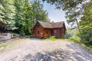 a log cabin in the woods with a dirt road at Cabin in the Vermont Woods in Hyde Park