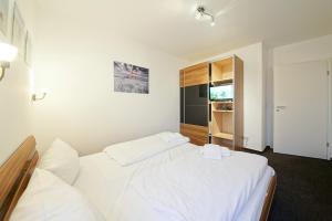 1 dormitorio con 2 camas blancas y TV en NordseeResort Friesland NordseeResort Friesland 51-1-S, en Schillig