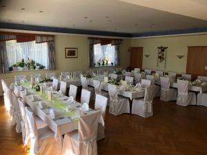 a banquet hall with white tables and chairs in a room at Goldsberghof in Pöllauberg