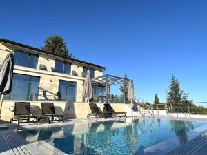 a pool with chairs and umbrellas next to a building at Villa Balchik in Balchik