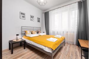 een slaapkamer met een bed met gele lakens en een raam bij Siewierska 17 by Homeprime in Warschau