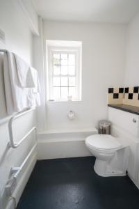 a white bathroom with a toilet and a window at Bell Hotel by Greene King Inns in Tewkesbury