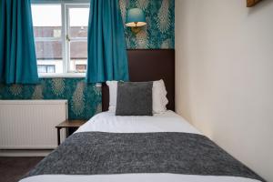 圖克斯伯里的住宿－Bell Hotel by Greene King Inns，一间卧室配有一张带蓝色窗帘的床和一扇窗户