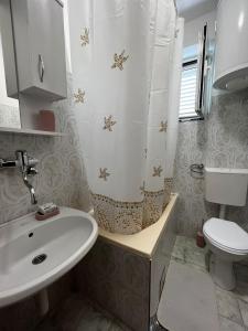a bathroom with a sink and a toilet and a shower curtain at Green place in Bar