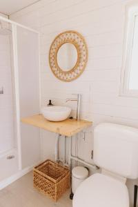 a bathroom with a sink and a mirror and a toilet at Dreamsea Bungalows Alentejo in Porto Covo