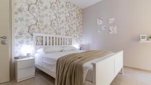 een slaapkamer met een wit bed met een deken erop bij Le stanze dei Pico Wi-Fi, Netflix e una terrazza unica sul tetto in Mirandola