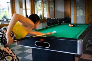 a woman playing a game of pool on a pool table at Hotel Pian del Sole in Sassello