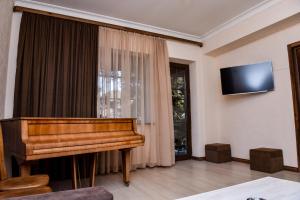Il comprend un salon avec un piano et une télévision à écran plat. dans l'établissement Maestro Rest House Dilijan, à Dilidjan
