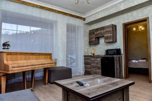 a living room with a piano and a kitchen at Maestro Rest House Dilijan in Dilijan