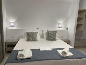 Una cama blanca con toallas y sombreros. en Hotel Kourkoumelata en Argostoli
