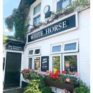 a white house with a white horse sign and flowers at The White Horse Crostwick in Norwich