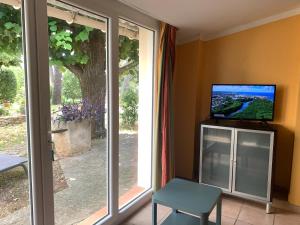 - un salon avec une télévision et une porte coulissante en verre dans l'établissement Mazet proche Golf, à Nîmes