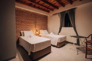 een slaapkamer met 2 bedden en een bakstenen muur bij Pine View Hotel (Okella) in Saittas