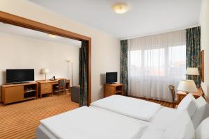 a hotel room with two beds and a desk at Danubius Hotel Raba in Győr