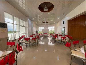 um salão de banquetes com mesas, cadeiras e arcos vermelhos em Pilot Hotel powered by Cocotel em Alaminos