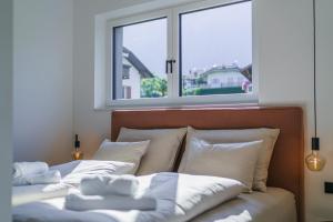 Una cama con almohadas blancas frente a una ventana. en Auszait Apartments 2, en Caldaro