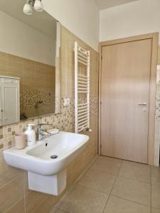 een badkamer met een witte wastafel en een spiegel bij La Chiostrina by TraMonti Apartments in LʼAquila