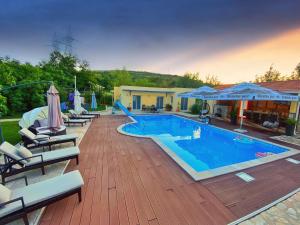 uma grande piscina com cadeiras e guarda-sóis ao lado de uma casa em APARTMENTS LA NATURE MOSTAR-HODBINA em Mostar