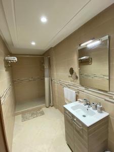 y baño con lavabo, ducha y espejo. en Charmant Appartement au Cœur de la Ville, en Marrakech