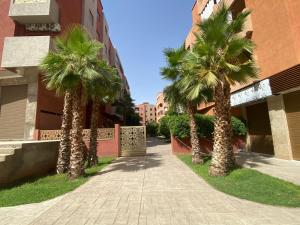 una acera con palmeras frente a un edificio en Charmant Appartement au Cœur de la Ville en Marrakech
