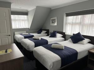 three beds in a room with blue and white at Corner House Hotel Gatwick with Holiday Parking in Horley