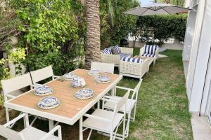 una mesa de madera con sillas blancas y una sombrilla en Sindbad House, en La Marsa