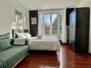 Un dormitorio con una cama y un sofá y una ventana. en Résidence 4T - 33 bis Avenue Gaston Chauvin, en Aulnay-sous-Bois