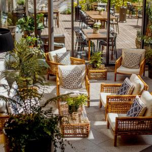 eine Terrasse mit Korbstühlen, Tischen und Pflanzen in der Unterkunft Sunlight Hotel Conference & Spa in Nyköping