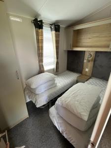 a bedroom with two beds and a window at 6 birth caravan chapel st Leonards trunch lane in Chapel Saint Leonards
