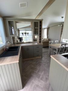 a kitchen with white cabinets and a dining room at 6 birth caravan chapel st Leonards trunch lane in Chapel Saint Leonards