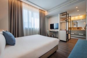 una camera d'albergo con letto e scrivania di IH Hotels Milano Centrale a Milano