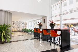 a lobby with a bar with orange chairs at IH Hotels Milano Centrale in Milan