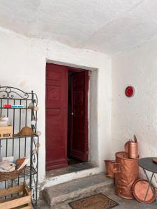 eine rote Tür in einem weißen Zimmer mit einem Tisch in der Unterkunft Gite casa mea in Santa-Lucia-di-Mercurio