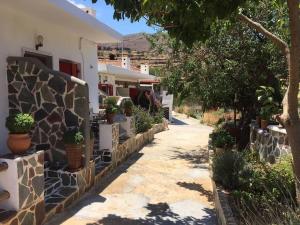 a walkway next to a house with potted plants at red guesthouse in Flampouria