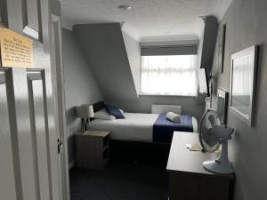 a small bedroom with a bed and a window at Corner House Hotel Gatwick with Holiday Parking in Horley