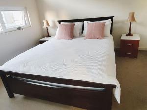 a bedroom with a large bed with white sheets and pink pillows at The Elands in Northfield