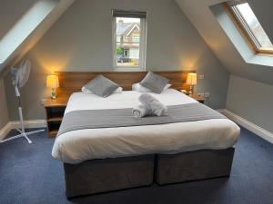 a bedroom with a large bed with a stuffed animal on it at Corner House Hotel Gatwick with Holiday Parking in Horley