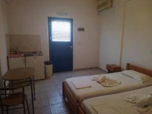 um quarto com duas camas e uma mesa e uma porta azul em Armenaki em Azolimnos