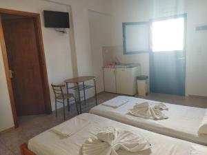 um quarto com duas camas e uma mesa e cadeiras em Armenaki em Azolimnos